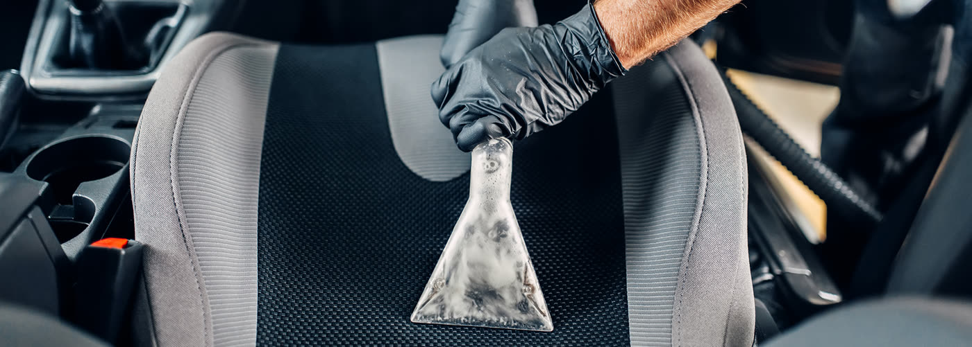 Detailer extracting a car seat with a steam cleaner